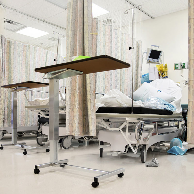 Hospital emergency room bays separated by privacy curtains with waste piled on the bed